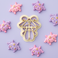 Kawaii demon ram clay cutter with colorful finished polymer clay charms on lavender background