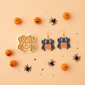 Pumpkin spider clay cutter with finished polymer clay earring sample on orange Halloween background