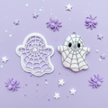 Spiderweb ghost clay cutter with finished polymer clay charm on pastel lavender kawaii background