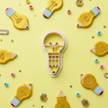 Lightbulb pencil clay cutter with colorful finished polymer clay charms on yellow background